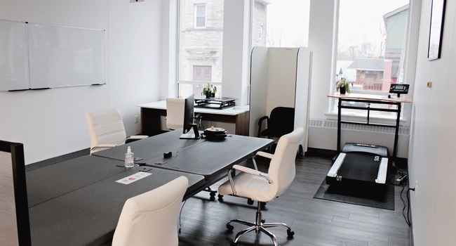 Assorted tables and chairs in an office space with a walking treadmill in the corner