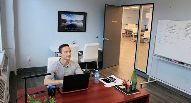 A man in an office looking up while working at a laptop