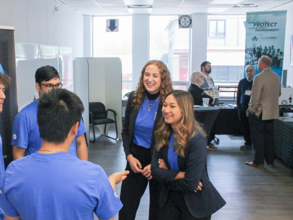 Five student interns talking in a group at a networking event